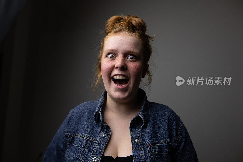 Happy and surprised redhead teenager, with her mouth and eyes wide open, after hearing some great news.